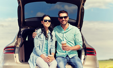 Image showing happy couple with coffee at hatchback car trunk