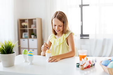 Image showing happy girl coloring easter eggs at home