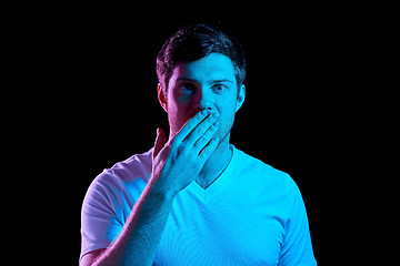 Image showing man covering his mouth by hand in neon lights