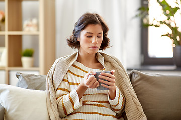 Image showing sad sick young woman drinking hot tea at home