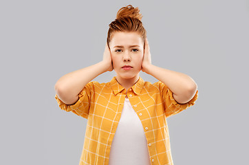 Image showing red haired teenage girl closing ears by hands