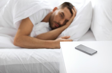 Image showing smartphone on bedside table near sleeping man