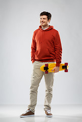 Image showing smiling young man in hoodie with short skateboard