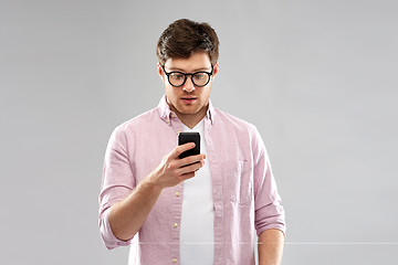 Image showing surprised man in glasses looking at smartphone