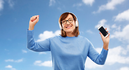 Image showing senior woman in headphones listening music on cell