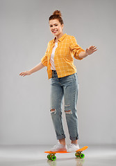 Image showing red haired teenage girl riding on short skateboard