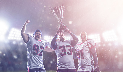 Image showing american football team with trophy celebrating victory in the cu