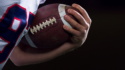 Image showing American football player holding ball while running on field