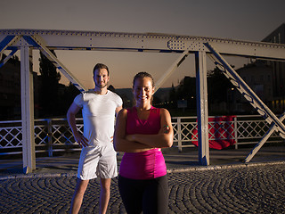 Image showing portrait of couple jogging across the bridge in the city