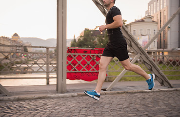 Image showing man jogging across the bridge at sunny morning