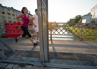 Image showing young couple jogging across the bridge in the city