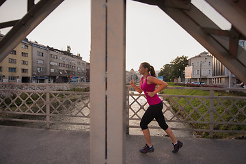 Image showing woman jogging across the bridge at sunny morning