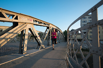 Image showing woman jogging across the bridge at sunny morning