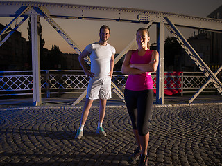 Image showing portrait of couple jogging across the bridge in the city