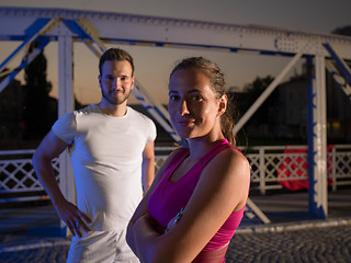 Image showing portrait of couple jogging across the bridge in the city