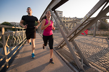 Image showing young couple jogging across the bridge in the city