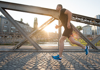 Image showing man jogging across the bridge at sunny morning