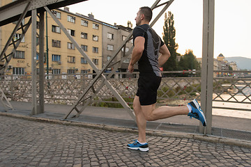 Image showing man jogging across the bridge at sunny morning