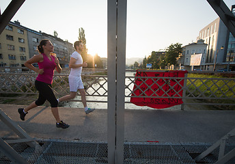 Image showing young couple jogging across the bridge in the city