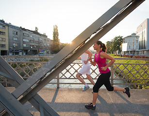 Image showing young couple jogging across the bridge in the city