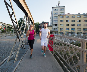 Image showing young couple jogging across the bridge in the city