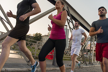 Image showing group of young people jogging across the bridge