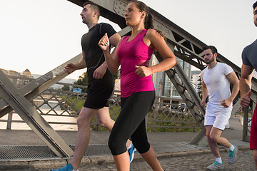 Image showing group of young people jogging across the bridge