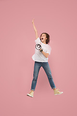 Image showing Beautiful young woman jumping with megaphone isolated over pink background