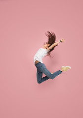 Image showing Freedom in moving. Pretty young woman jumping against pink background