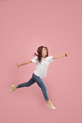 Image showing Freedom in moving. Pretty young woman jumping against pink background