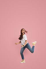 Image showing Freedom in moving. Pretty young woman jumping against pink background