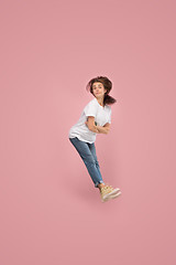 Image showing Freedom in moving. Pretty young woman jumping against pink background