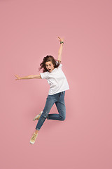 Image showing Freedom in moving. Pretty young woman jumping against pink background