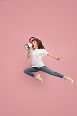 Image showing Beautiful young woman jumping with megaphone isolated over pink background