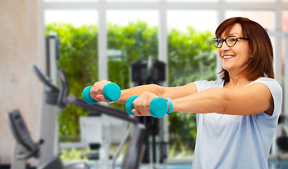 Image showing happy old woman with dumbbells exercising in gym