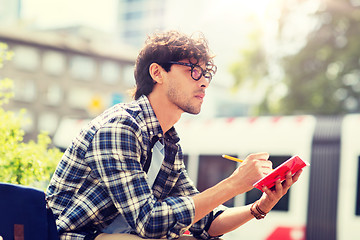 Image showing man with notebook or diary writing on city street