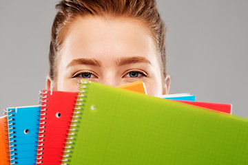 Image showing close up of teenage student girl behind notebooks