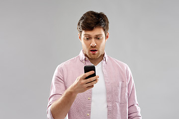 Image showing embarrassed young man looking at smartphone