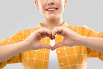 Image showing smiling teenage girl making heart gesture