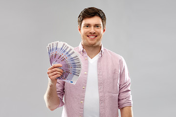 Image showing smiling young man with fan of euro money over grey