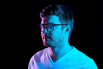 Image showing man in glasses over neon lights in dark room