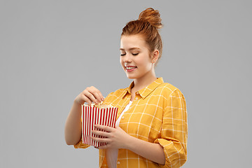 Image showing smiling red haired teenage girl eating popcorn