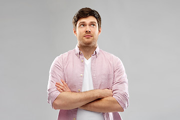 Image showing suspecting young man with crossed hands looking up