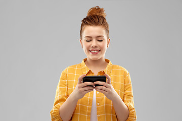 Image showing smiling red haired teenage girl using smartphone