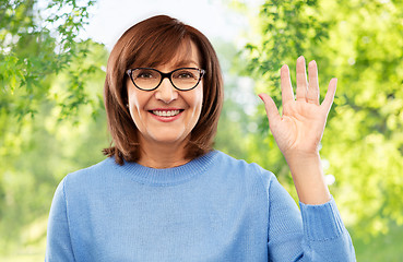 Image showing portrait of senior woman in glasses waving hand