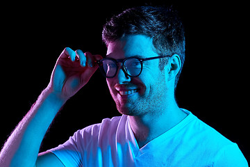 Image showing man in glasses over neon lights in dark room