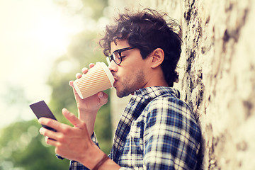 Image showing man with smartphone drinking coffee on city street