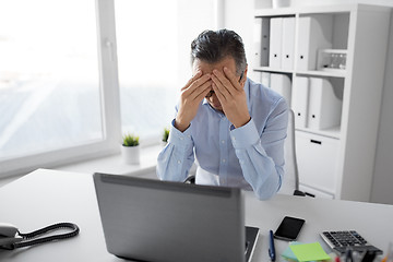 Image showing stressed businessman with laptop working at office