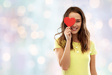 Image showing smiling teenage girl covering her eye by red heart