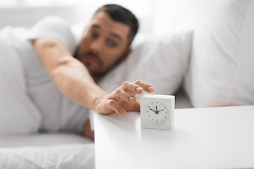 Image showing close up of man in bed reaching for alarm clock